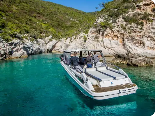 Our boat anchored in a turquoise cove ringed by white rock and pines
