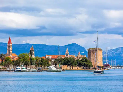 Trogir old town seen from the water, the cathedral tower and Kamerlengo fortress above moored boats